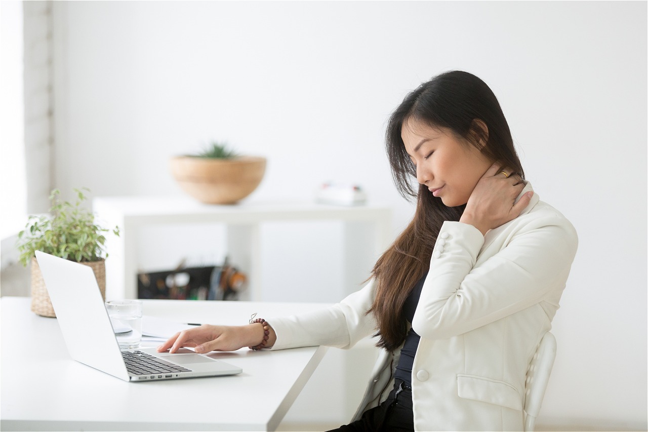 Woman stretches neck at desk